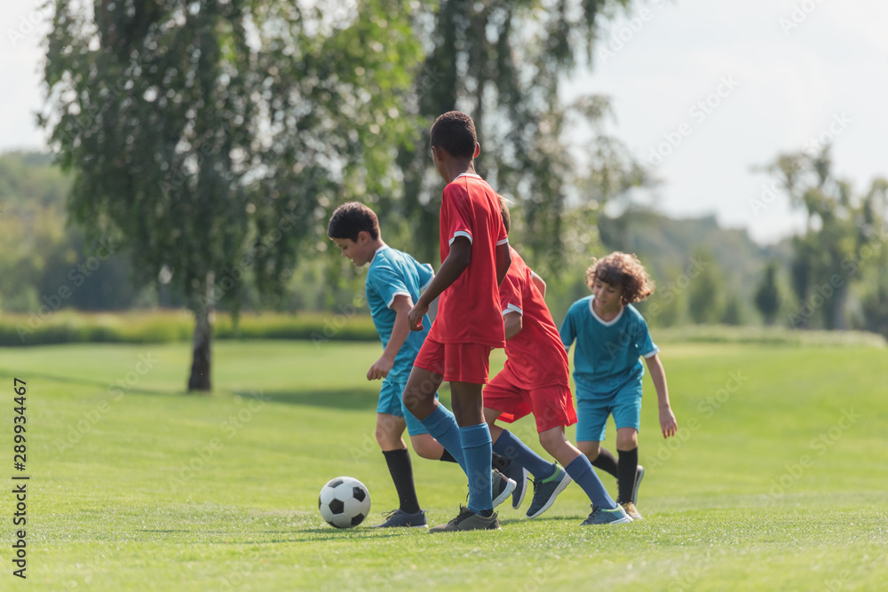 Obraz premium cute kids playing football with african american friend