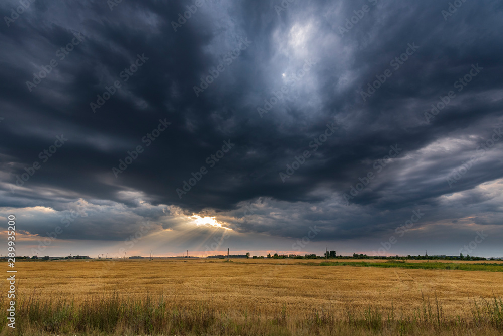 Dark storm sky and open agriculture field during sunset. Dark storm sky and open agriculture field during sunset.