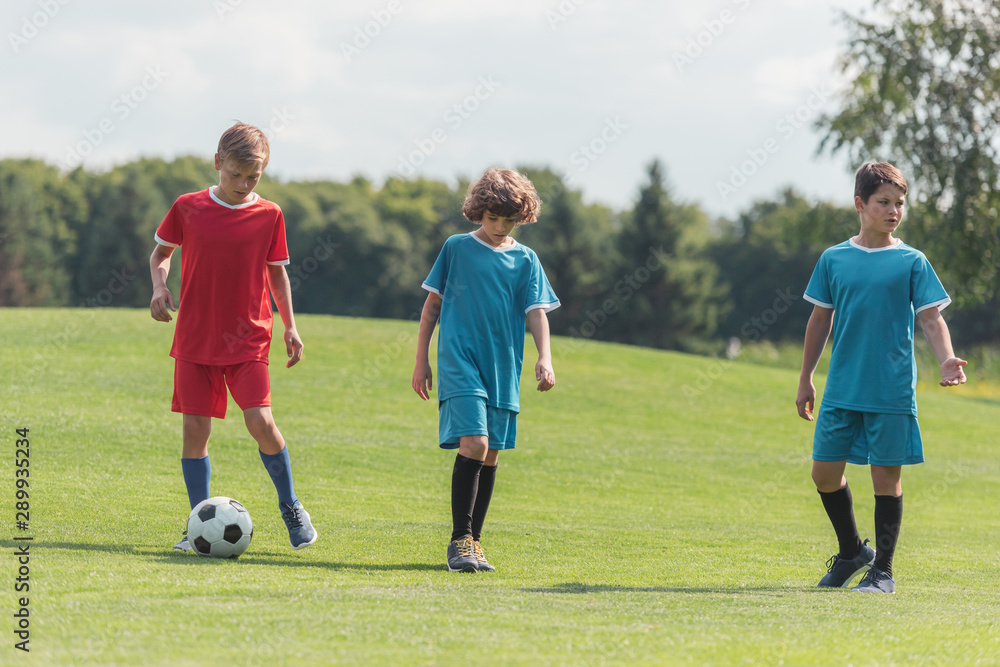 curly boy playing football with friends on green grass curly boy playing football with friends on green grass