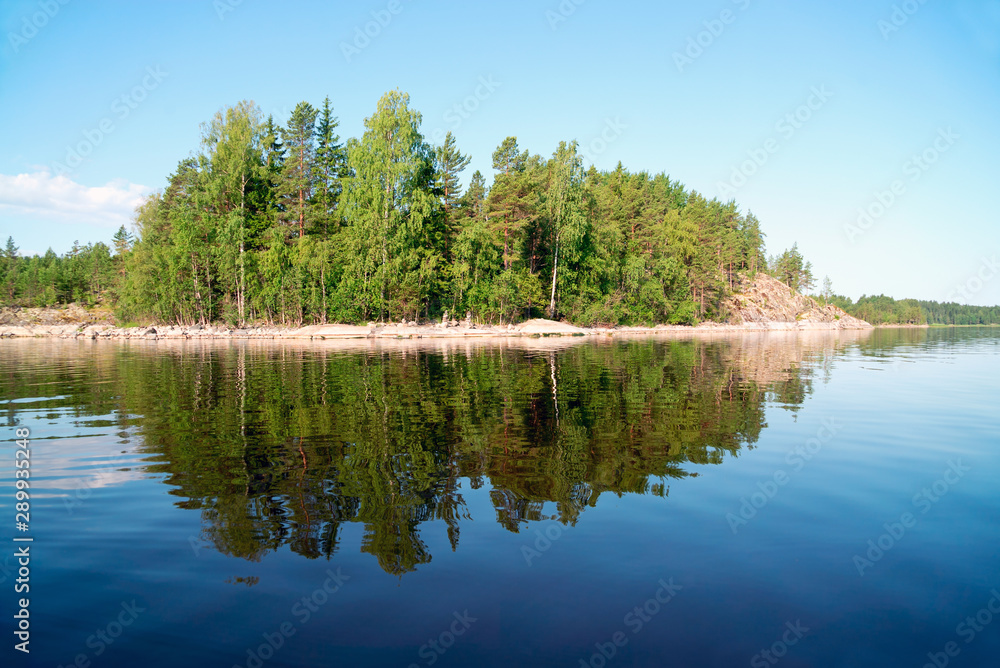 Fototapeta premium Stone island with a reflection in the water on the lake . Ladoga Skerries, Karelia.