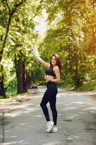 Cute girl training in a summer forest. Lady have fun in a park. Sports woman in a black sportsuit