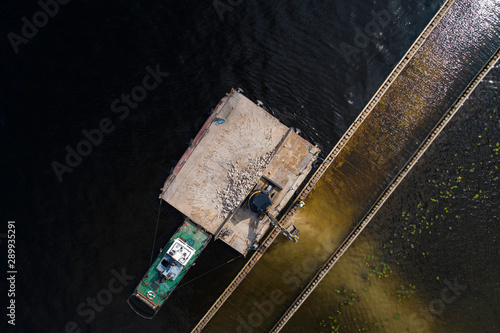 Aerial view of an excavator digging into water while located on a raft.