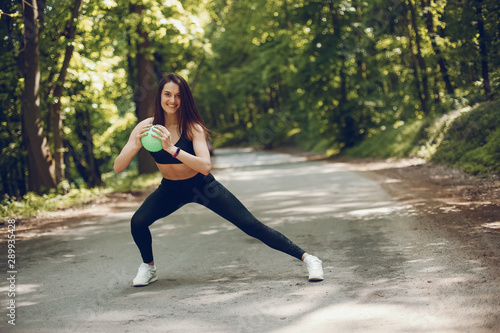 Cute girl training in a summer forest. Lady have fun in a park. Sports woman in a black sportsuit