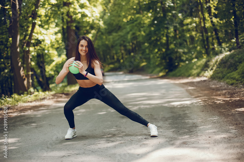 Cute girl training in a summer forest. Lady have fun in a park. Sports woman in a black sportsuit © hetmanstock2