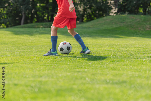 selective focus of kid in red sportswear playing football