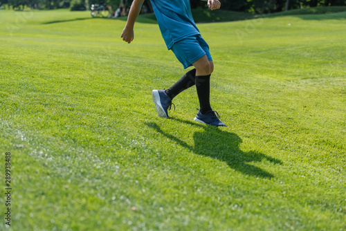 cropped view of kid running on green grass