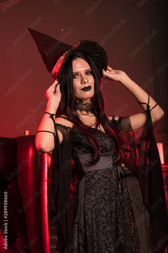 Charming witch in a dark room on Halloween Charming witch in a dark room on Halloween
