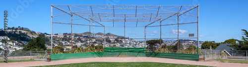 Photography Empty baseball infield with backstop against  cityscape and blue sky