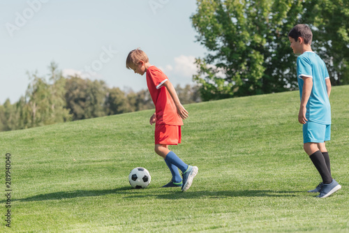 friends in sportswear playing football on grass