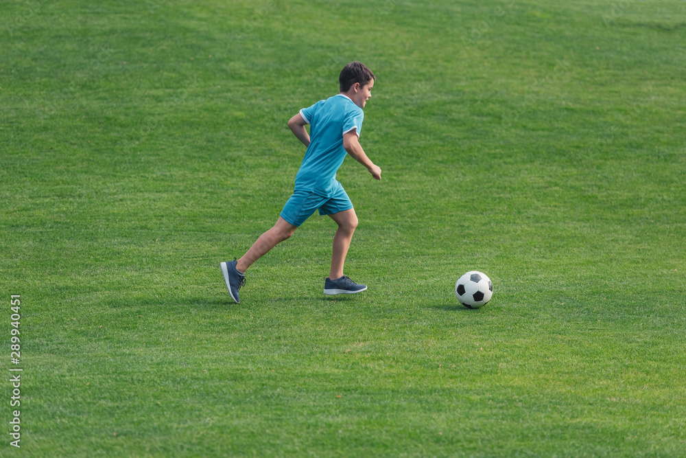 kid in sportswear running on green grass with football kid in sportswear running on green grass with football