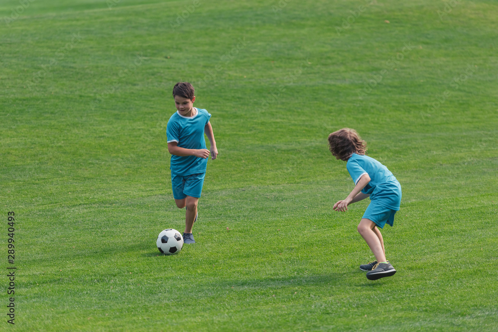 cute boys in sportswear playing football on grass cute boys in sportswear playing football on grass
