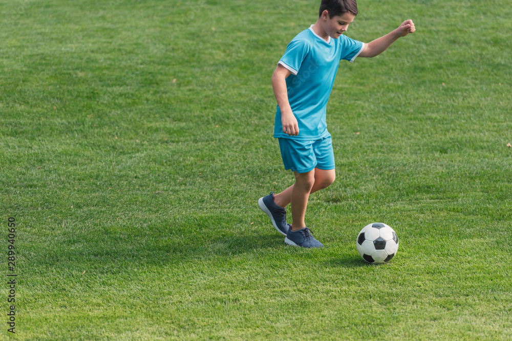cute boy in sportswear playing football on green grass cute boy in sportswear playing football on green grass