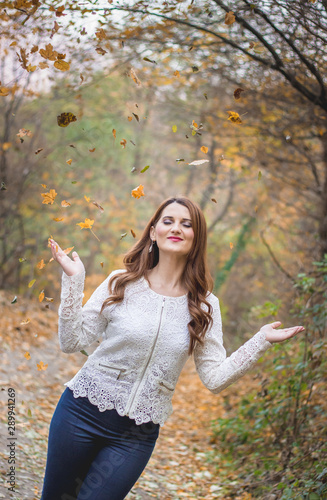 Girl in autumn walk, throwing leaves in air. Outdoors, nature, fall concept