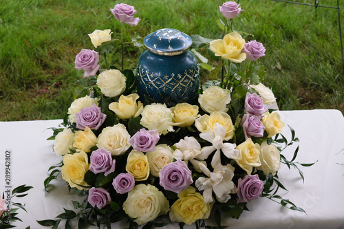 funeral and mourning concept - flowers surrounding urn  photo