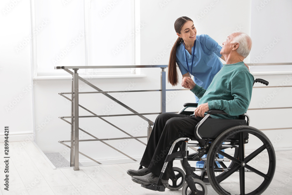 Nurse assisting senior man in wheelchair at hospital