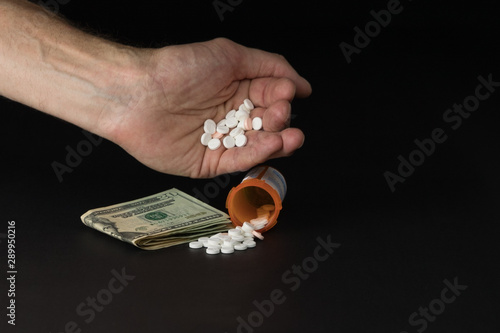 Prescription drugs in hand with money and pill bottle