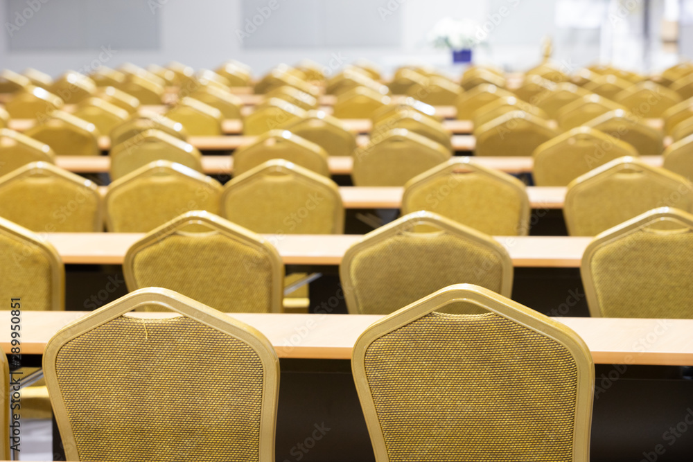 Fototapeta premium Stack Steel Chair Fabric seat pad yellow gold color and Table arrange in row ready to set up for big meeting, conference, business, workshop, gala dinner, Wedding ceremony in Convention Hall of Hotel