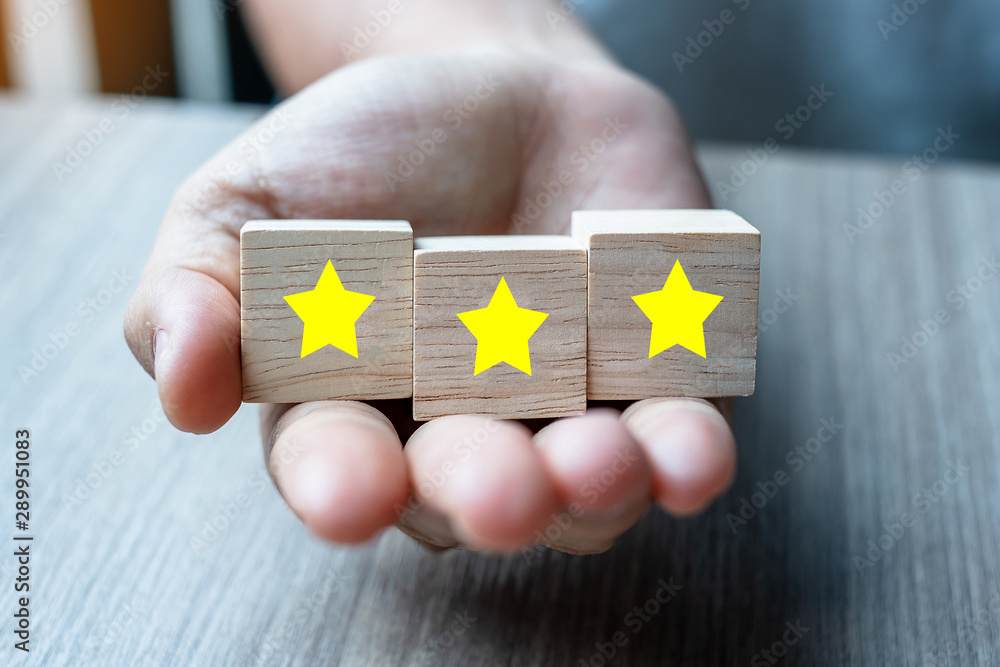 customer holding wooden blocks with the three star symbol. Customer reviews, feedback, rating, ranking and service concept.