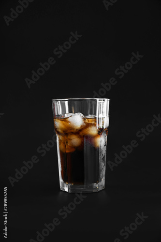 Glass of cold cola on dark background