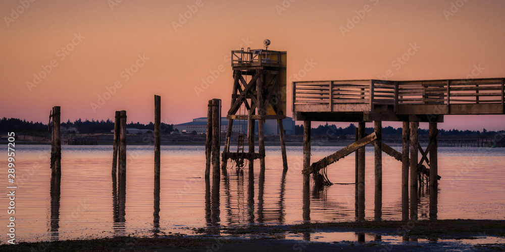 Sunset at Coos Bay Oregon Empire dock. Silhouetted wood pilings, industrial fishing wharf.