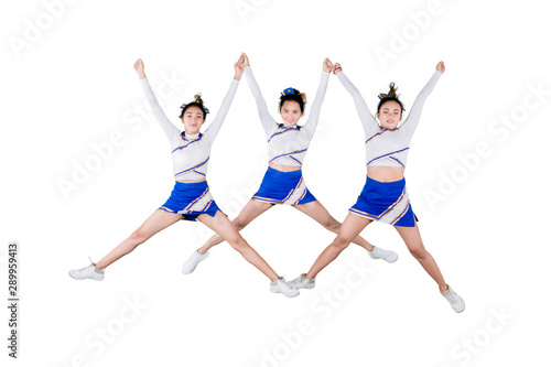 Pretty cheerleader team jumping together on studio