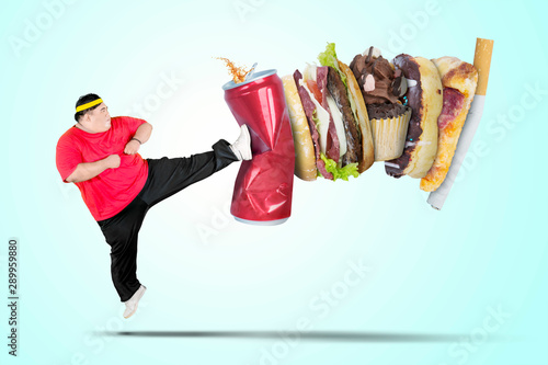 Young fat man kicking soft drink and fast food