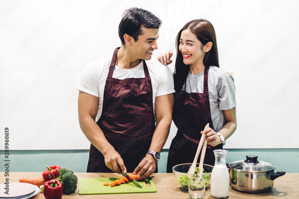 Happy couple cooking and preparing meal together in the kitchen