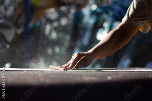 The craftsmen are using their hands to scrub the wooden boards with sandpaper which is very dusty © noprati