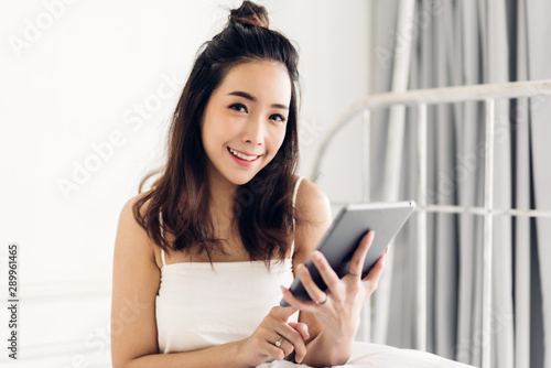 Happy woman relaxing using tablet computer on the bed at home.technology and communication concept