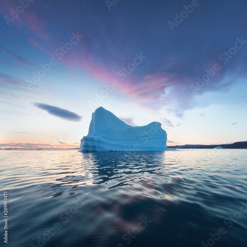 Iceberg at sunset. Nature and landscapes of Greenland. Disko bay. West Greenland. Summer Midnight Sun and icebergs. Big blue ice in icefjord. Affected by climate change and global warming. © Michal