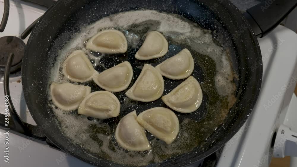 Pierogies bubbling while frying in butter on a stove Pierogies bubbling while frying in butter on a stove