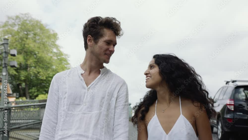 A young travelling couple walking hand in hand and laughing on a street. A young travelling couple walking hand in hand and laughing on a street.