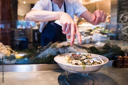 restaurant worker introducing oyster dish to customer