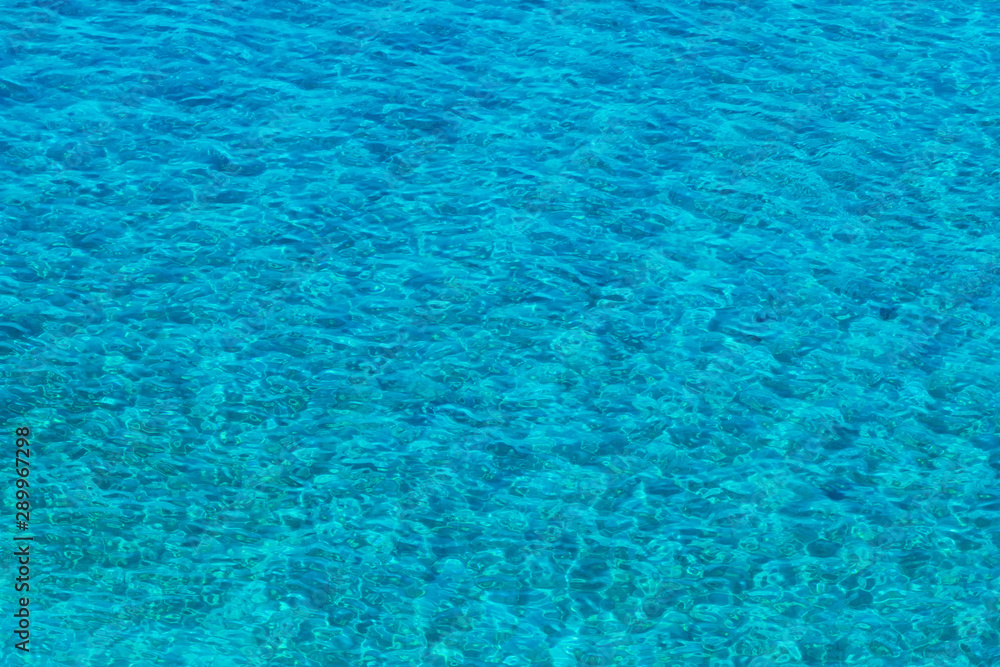Vibrant blue color surface of sea. Top view on clean sky blue sea water with small waves. Summer sea water texture background