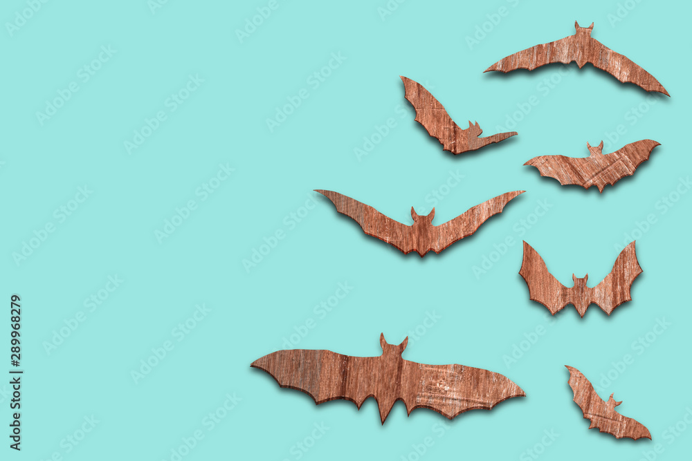 Fototapeta premium Halloween holiday concept - wooden bats flying over blue background