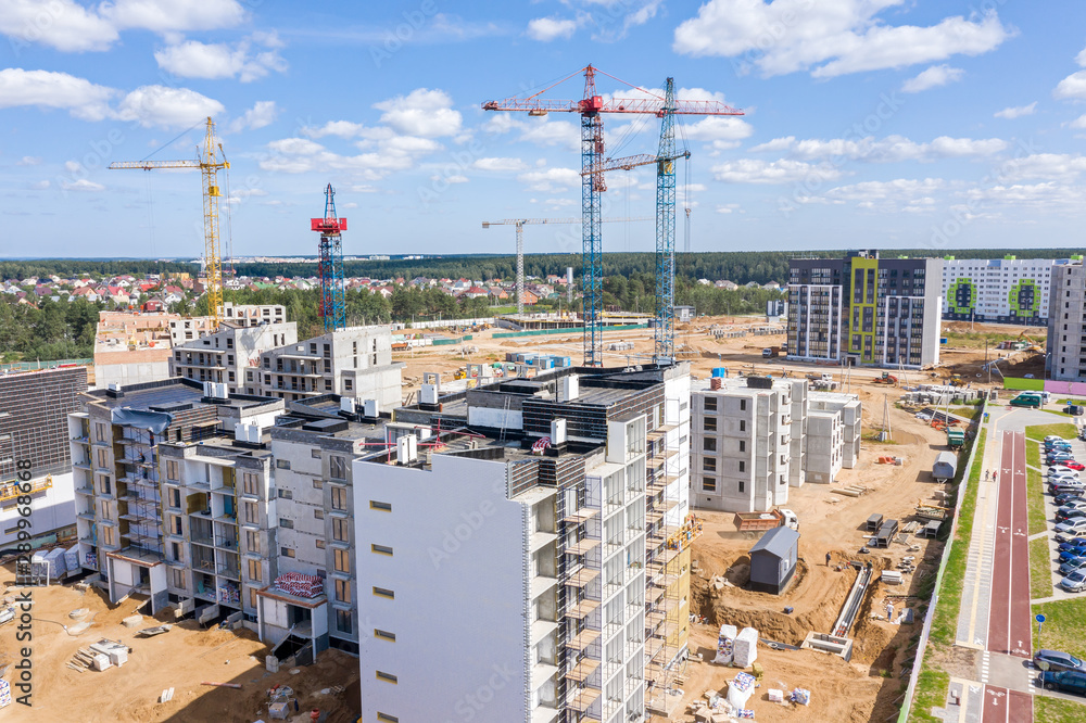 aerial view of newly built apartment buildings. tower cranes against blue sky background