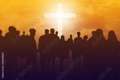 Silhouette crowd standing in front of white cross with sunset sky background. Christian faith and trust concept .