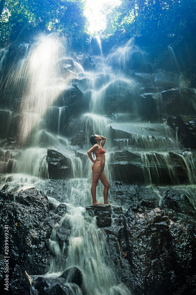 Fototapeta premium natural portrait of young beautiful and happy Asian Korean woman in bikini enjoying nature at tropical paradise waterfall with magical feeling in soul inspiration