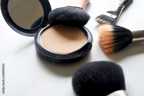 Makeup brush and powder placed on a white table.