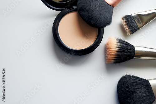Makeup brush and powder placed on a white table.