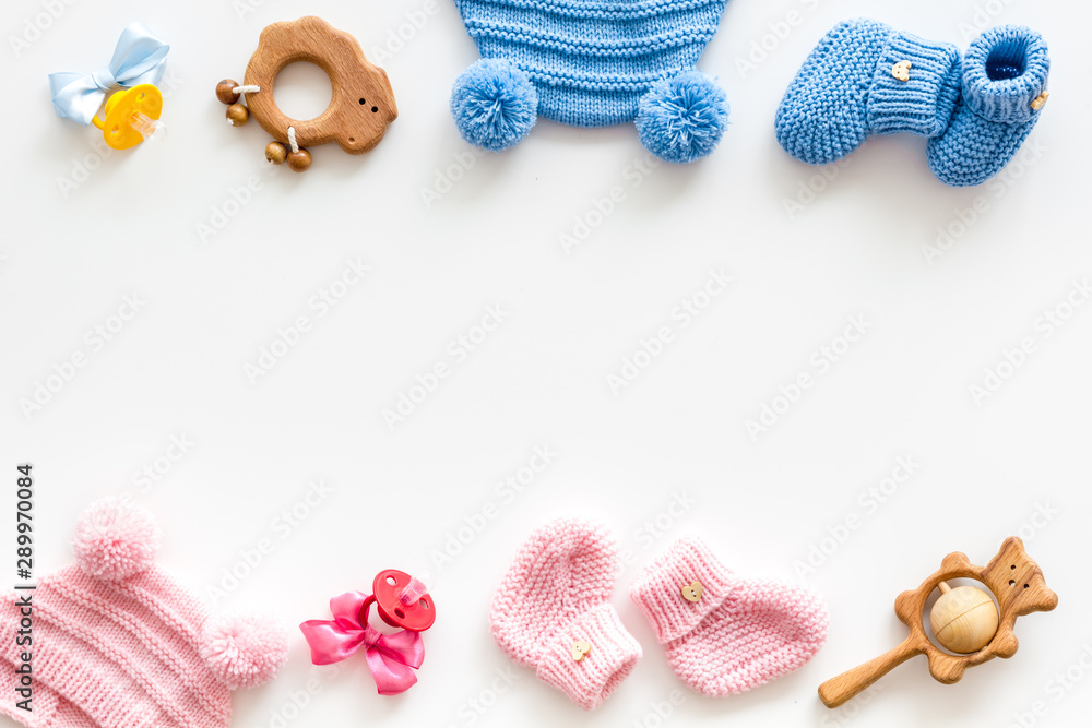 Blue and pink knitted footwear, hat, dummy, rattle frame for baby on white background top view mockup - obrazy, fototapety, plakaty 
