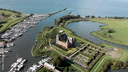 Aerial panning around the Muiderslot castle in Muiden near Amsterdam at the IJsselmeer with surrounding water entrenchment and port area next to the fortification photo