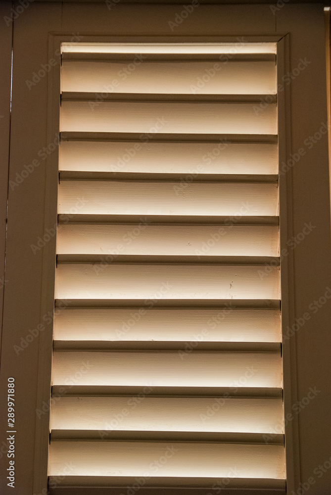 Soft light through wooden blind shutters in closed position. Soft light through wooden blind shutters in closed position.