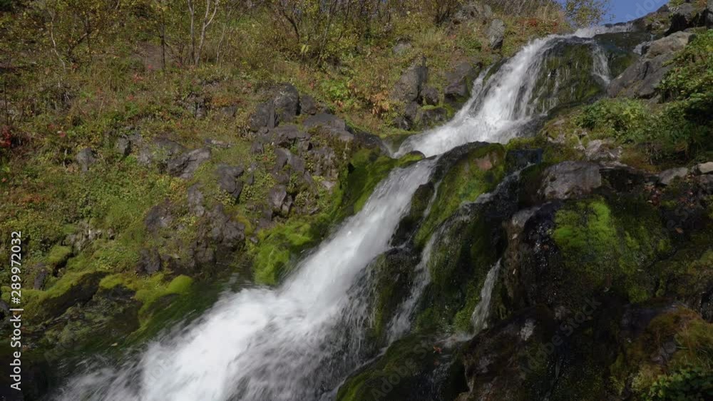Autumn environment landscape: cascade of alpine waterfall with crystal clean and clear splashing water flowing from glaciers in mountains. Concept: lack of clean drinking water. Tilt down movement. Autumn environment landscape: cascade of alpine waterfall with crystal clean and clear splashing water flowing from glaciers in mountains. Concept: lack of clean drinking water. Tilt down movement.