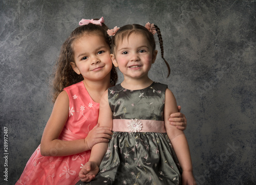 Portrait beautiful mixed race sisters in party dresses isolated on gray background © ShannonK
