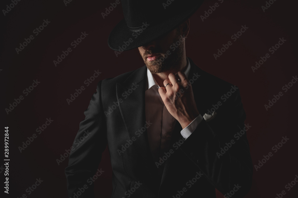 mysterious young man fixing collar on black background mysterious young man fixing collar on black background