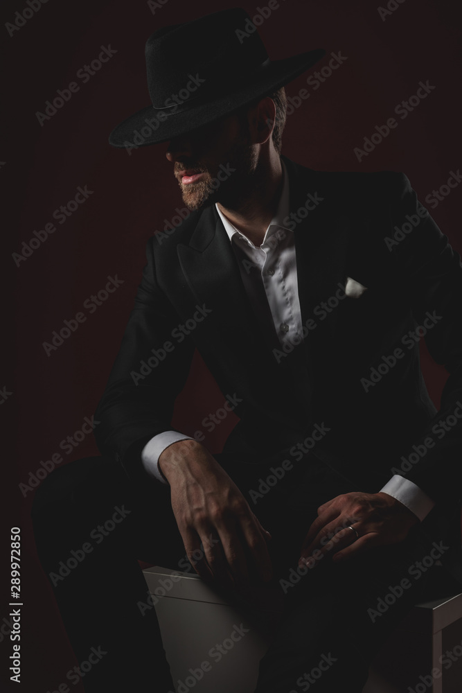 attractive young man sitting on white table and looking to side attractive young man sitting on white table and looking to side