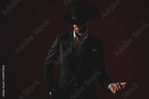 mysterious young man wearing tuxedo and presenting to side