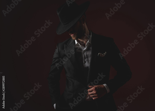 mysterious young man in tuxedo looking to side on black background