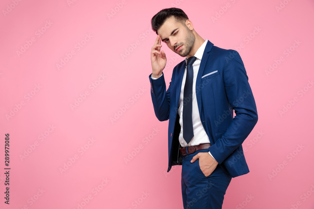 smart casual man pointing fingers to forehead on pink background smart casual man pointing fingers to forehead on pink background